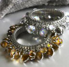Cuff bangles with beads from Plumo. Plumo Evantini cuff - Chic gold cuff made by an Italian designer artfully clustered with large ivory fashion pearls and round facetted Swarovski crystals. Made from gold plated brass, nickel free. Hand crafted in Italy. Plumo round tassel bracelets -Shimmering bracelets made from a multitude of round, faceted glass crystals. Elasticated for a perfect fit. Made from metal and glass. 